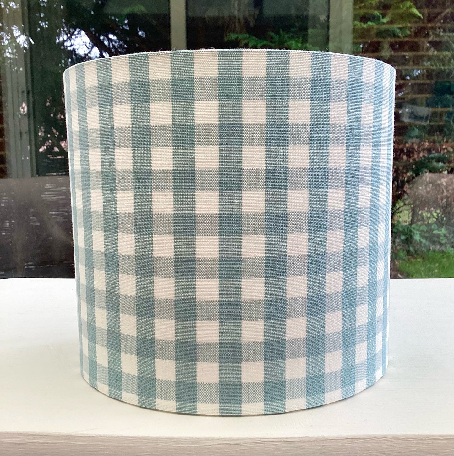 A charming duck egg blue gingham lampshade with a classic checkered pattern, perfect for adding a touch of vintage elegance to any room.