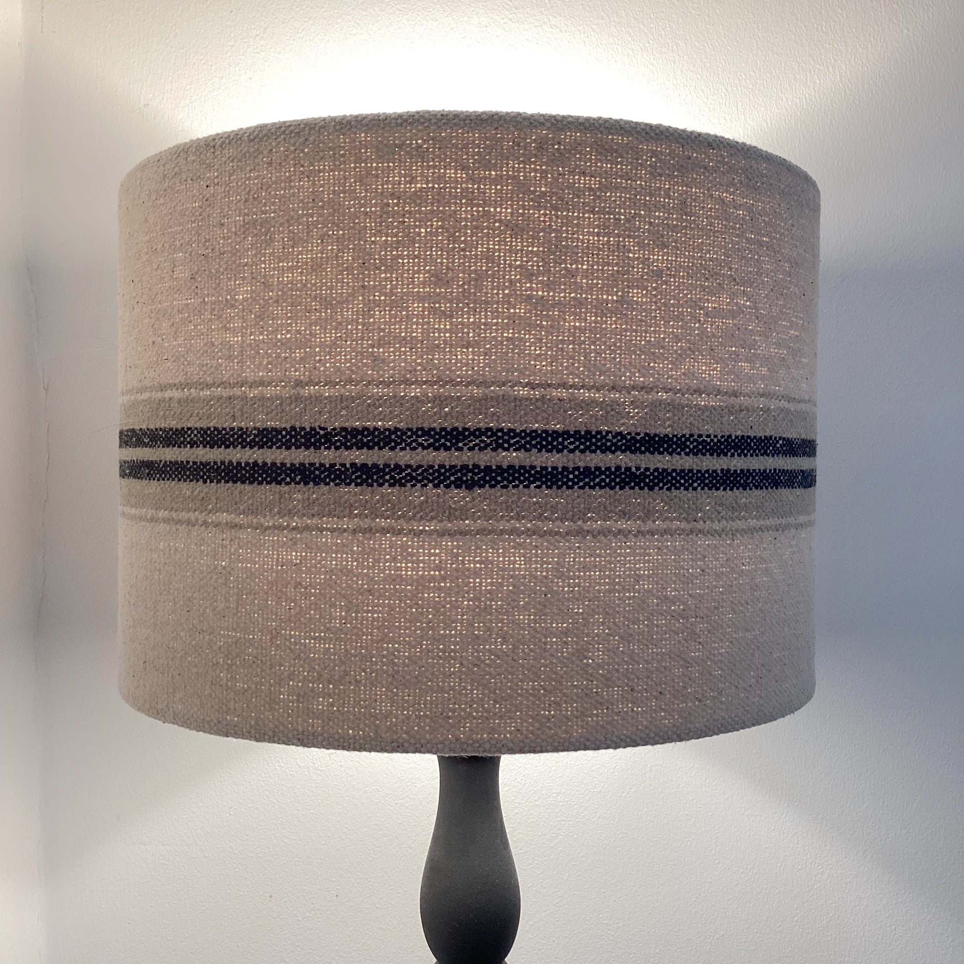 A close-up view of a luxurious, textured lampshade in soft beige, with a delicate geometric design and a subtle sheen, perfect for adding sophistication to any room.