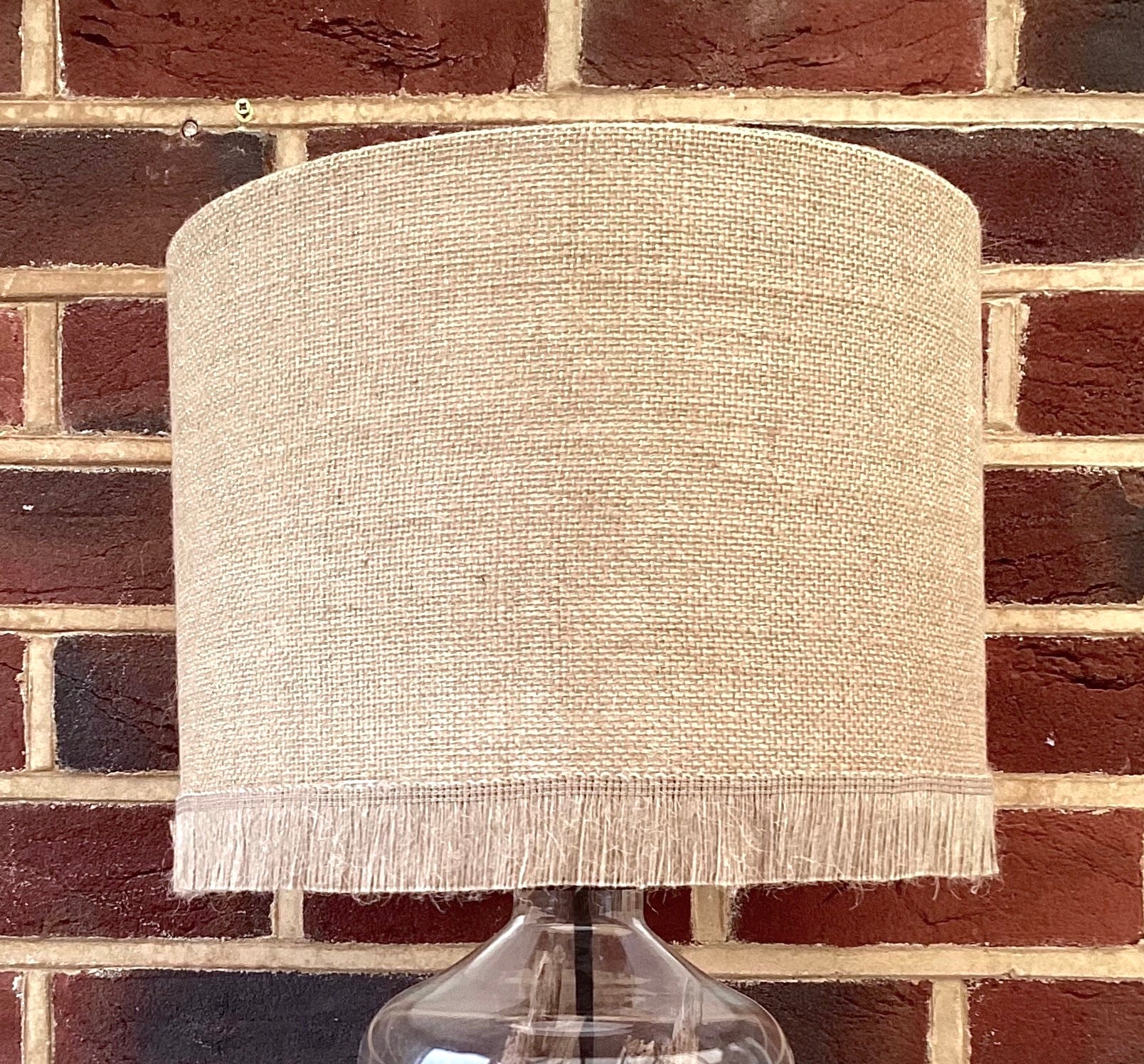 Natural hessian lampshade with a textured weave, offering a rustic and earthy aesthetic, perfect for adding warmth to any room.