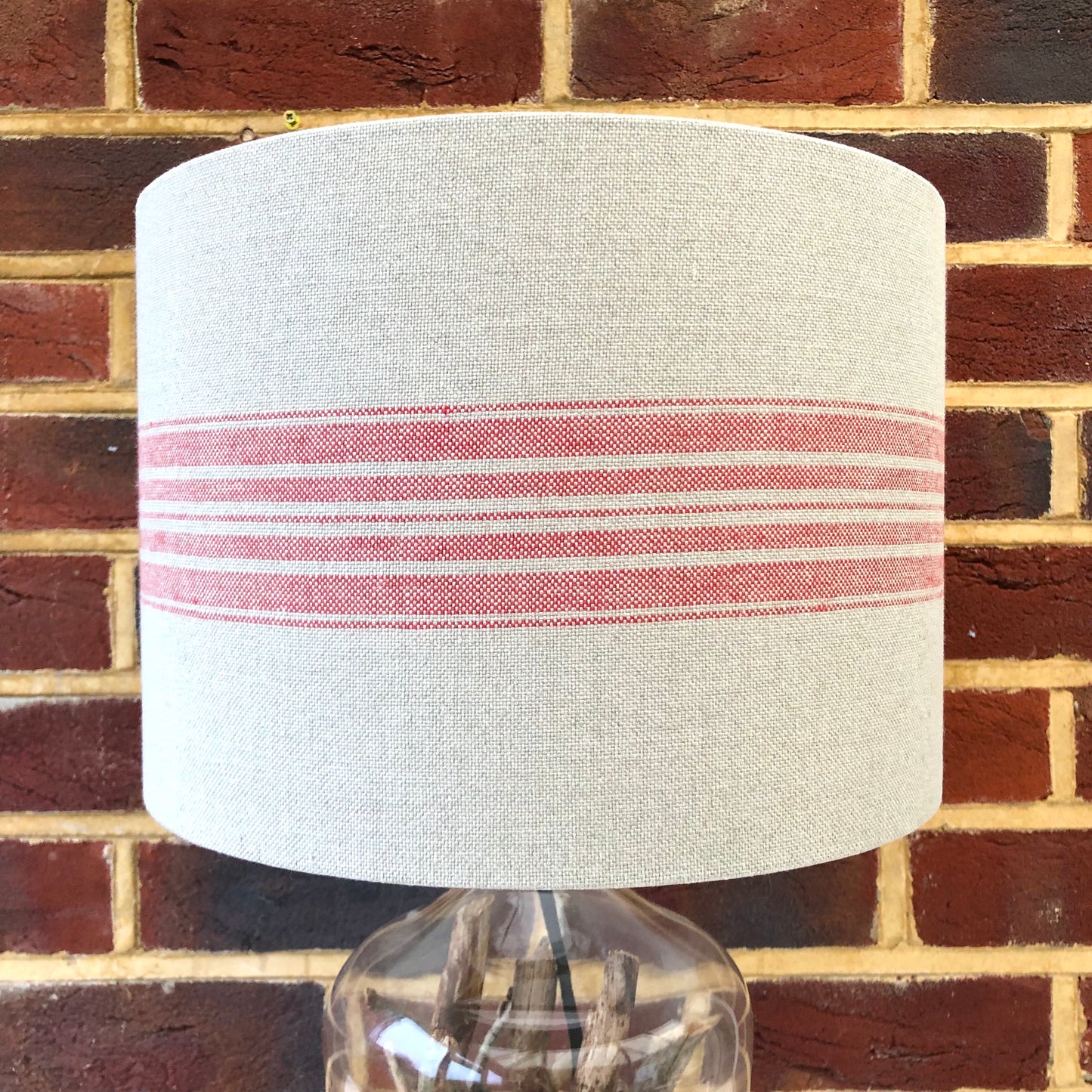 A stylish linen lampshade with bold red stripes, adding a pop of color and texture to any room’s decor.