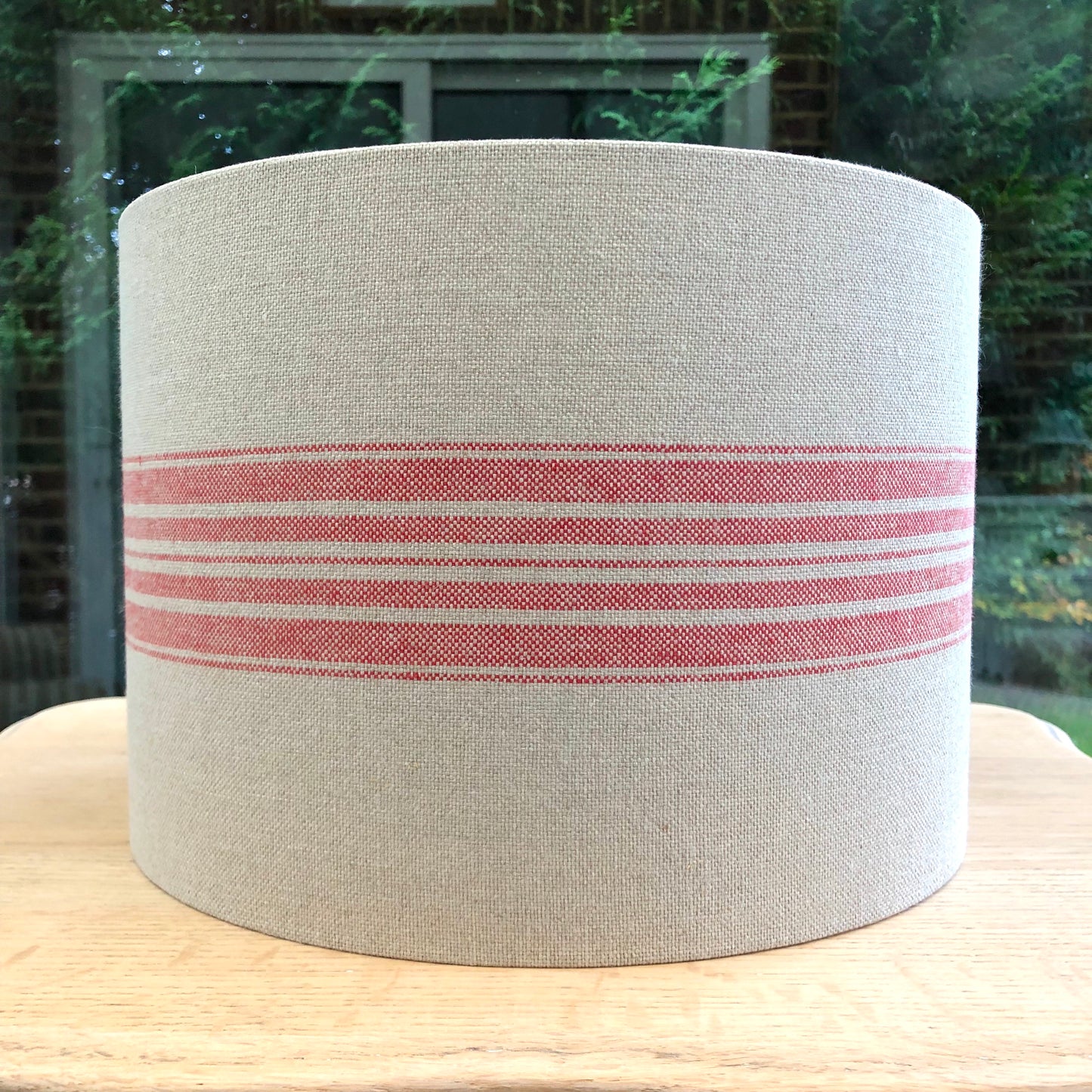A stylish linen lampshade with bold red stripes, adding a pop of color and texture to any room’s decor.