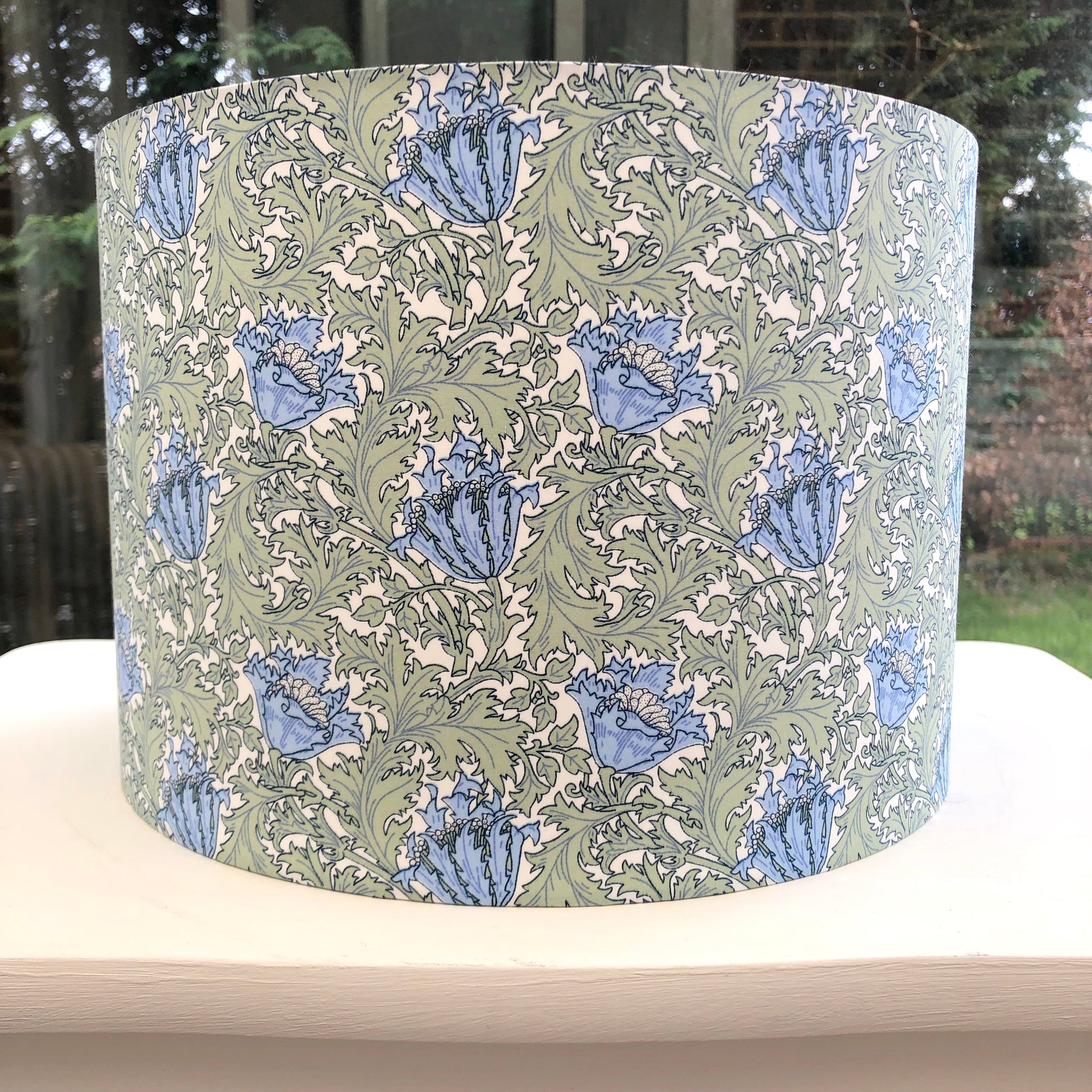 William Morris Anemone lampshade in green and blue, showcasing a classic floral design. Handcrafted with intricate patterns, perfect for adding vintage charm and elegance to any room decor.