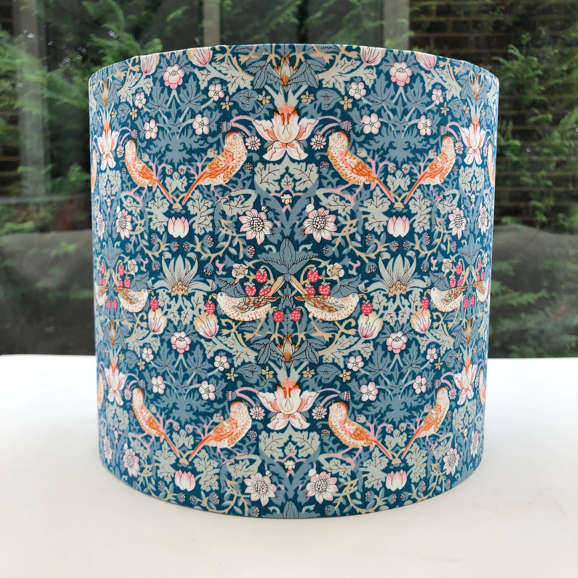 William Morris Strawberry Thief lampshade in green, blue, and pink, showcasing a vintage floral design. Perfect for adding a touch of classic elegance to any room decor.