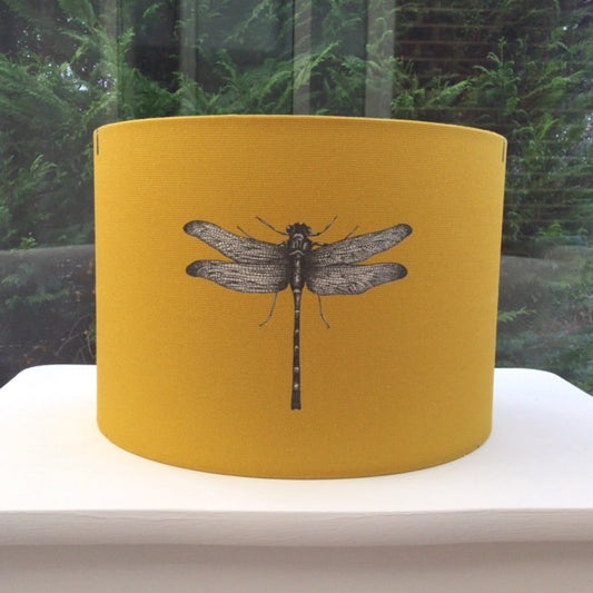 Handcrafted lampshade featuring a vibrant dragonfly design, illuminated by soft ambient light.