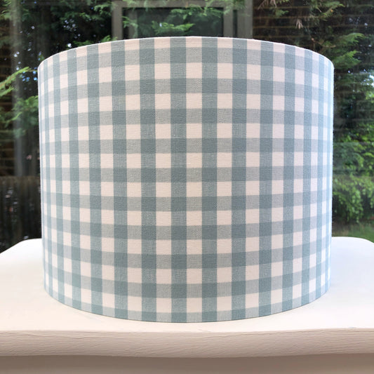 A charming duck egg blue gingham lampshade with a classic checkered pattern, perfect for adding a touch of vintage elegance to any room.