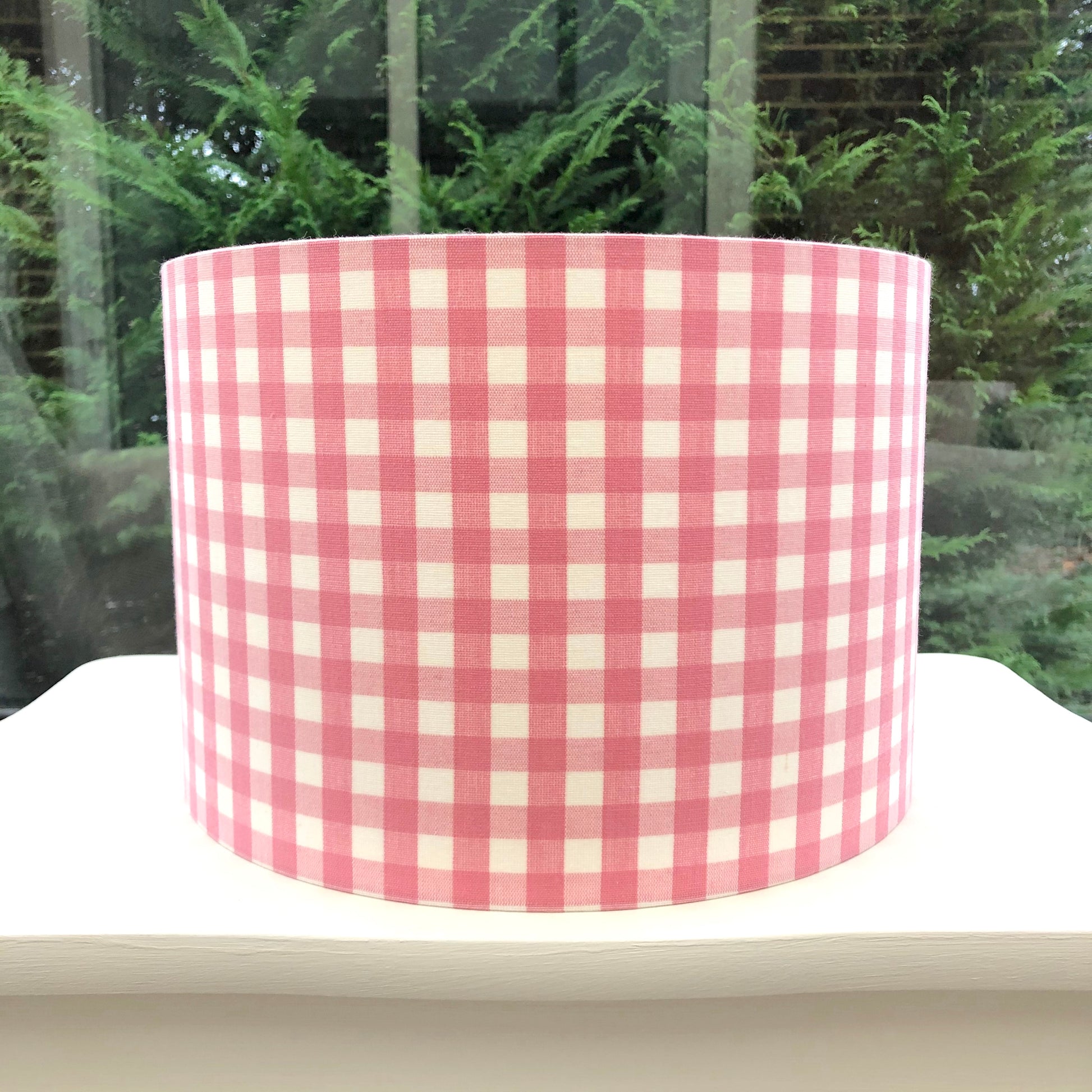 Pink coloured gingham-patterned lampshade, adding a touch of rustic charm to any space.