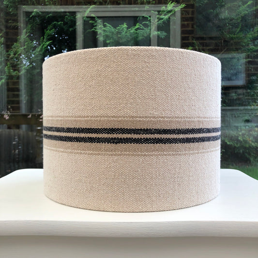 A close-up view of a luxurious, textured lampshade in soft beige, with a delicate geometric design and a subtle sheen, perfect for adding sophistication to any room.