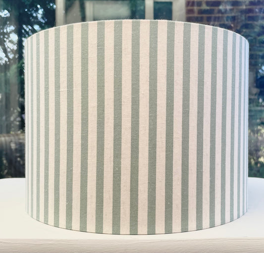 A stylish lampshade with a textured linen fabric in soft green, showcasing a modern yet classic design, perfect for adding warmth and sophistication to any room.