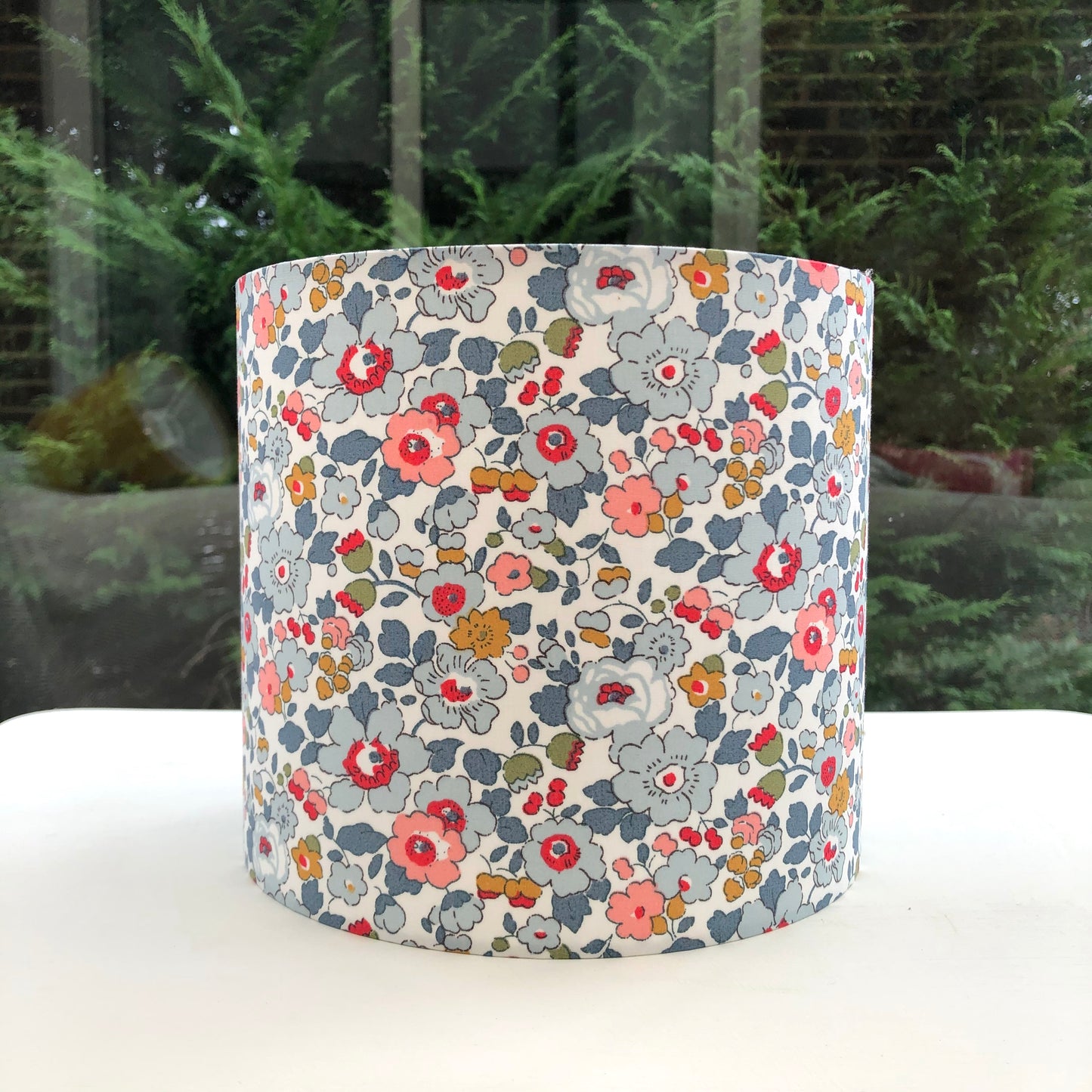 Charming grey lampshade with delicate, multicolored floral patterns in shades of pink, blue, and yellow, designed to bring a touch of whimsy and elegance to any room.