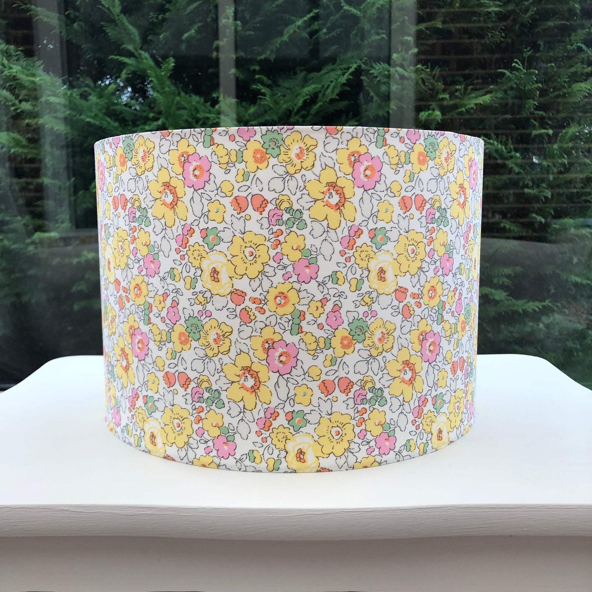 Bright yellow floral lampshade with a Liberty Betsy pattern, showcasing vibrant, detailed flowers in cheerful hues, adding a lively touch to any room.