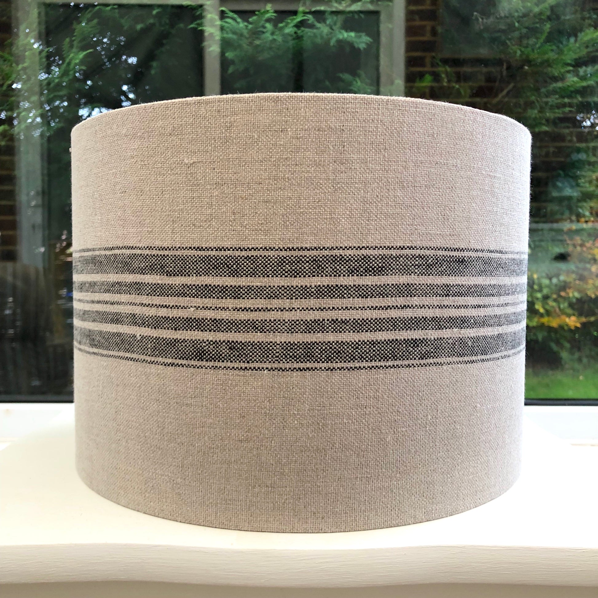 Stylish linen lampshade with black stripes, offering a modern and sophisticated design to complement contemporary home decor.