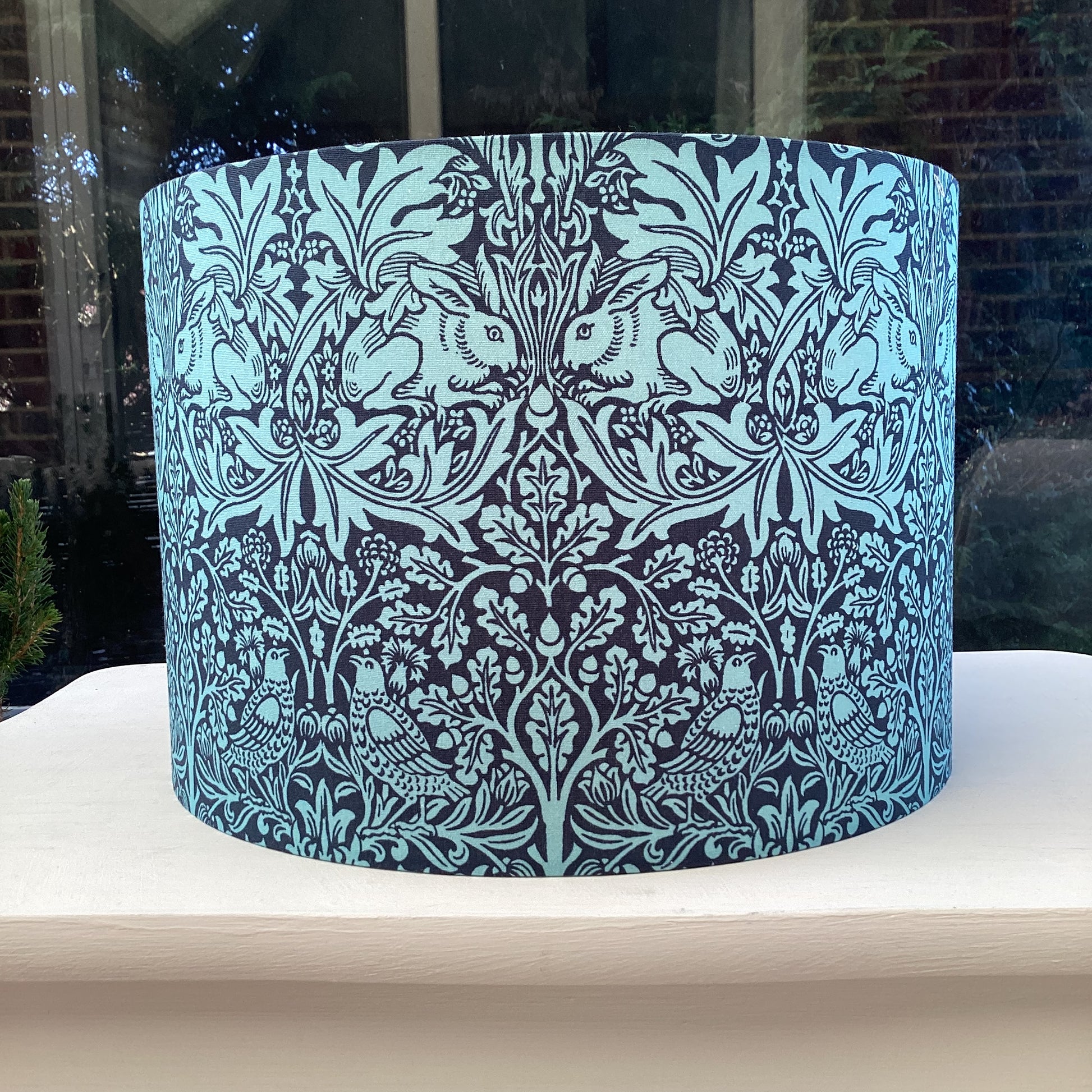 A lampshade featuring a whimsical Brer Rabbit design in navy and teal colors, adding charm to any space.